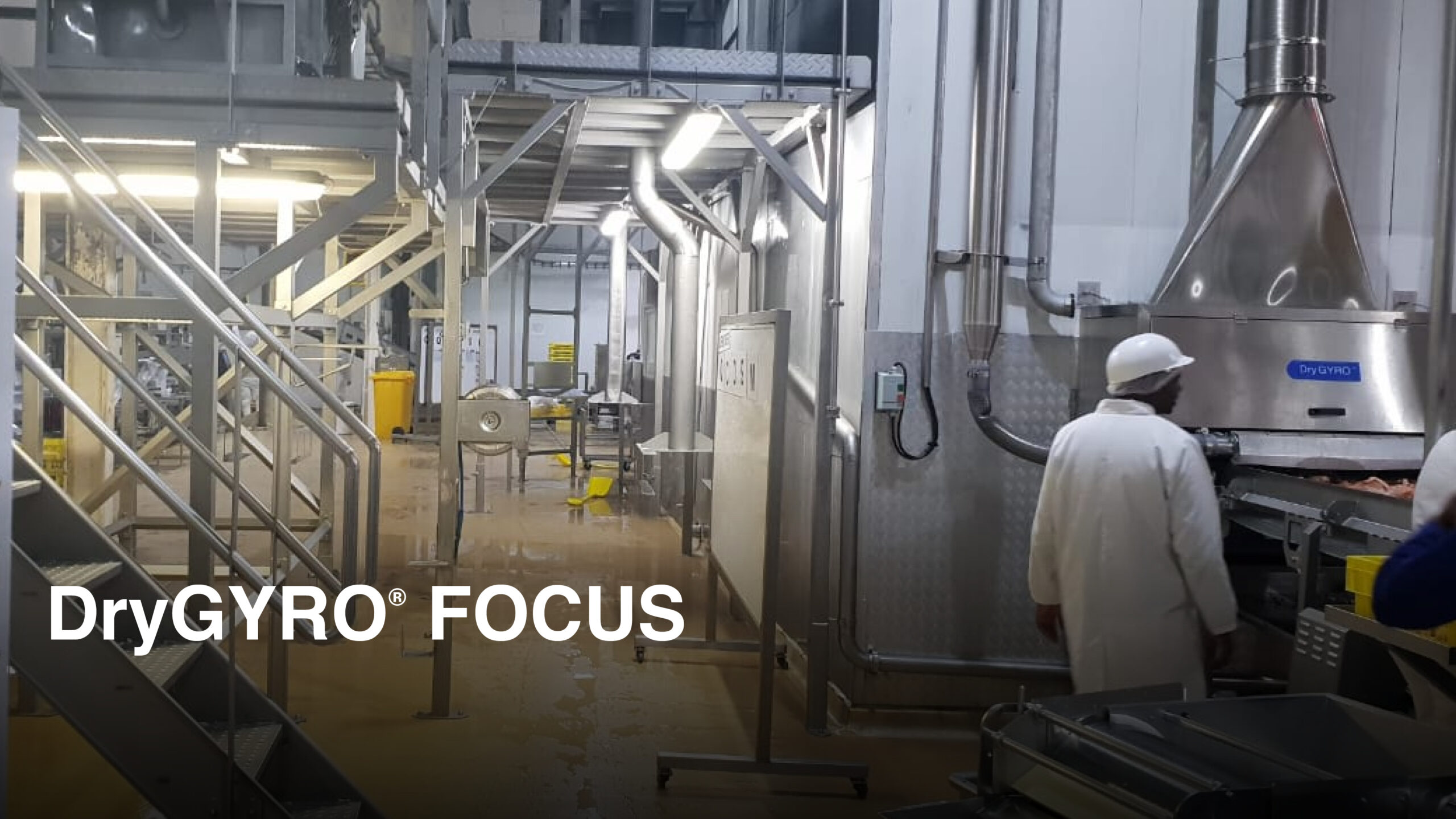 Industrial food processing facility featuring the DryGYRO® moisture control system installed alongside a conveyor freezer line, with workers operating in a chilled production environment.